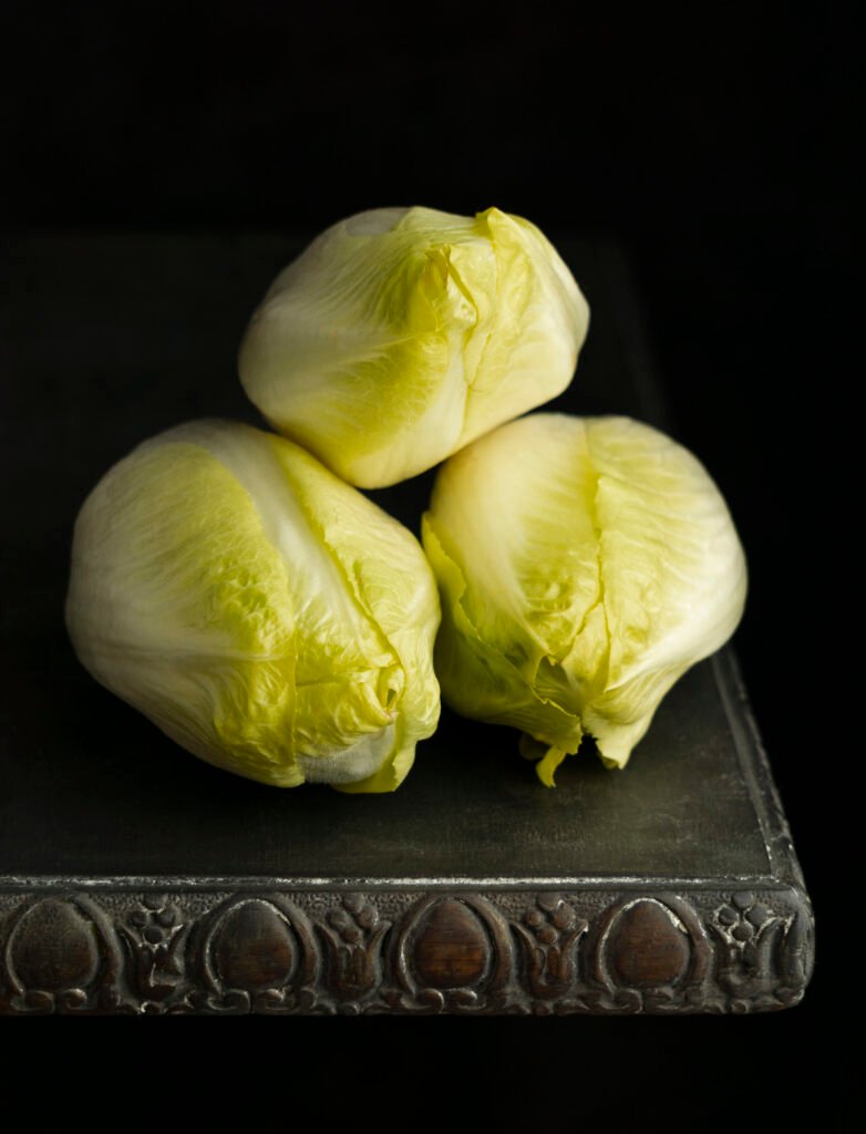 Three fresh Chinese cabbages stacked on top of each other, showcasing their crisp green leaves and firm white stalks.